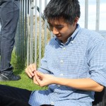 Johnny Huynh, '14 and Mathematical Economics major, braiding flowers into his buttons while taking a break by the coast