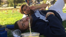 Friends lying on grass drinking from plastic cup