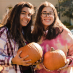 Sophia with friend, holding pumpkins