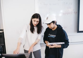 professor explaining something to student on laptop