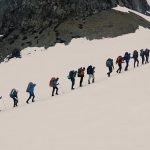 a line of people hiking up a snow-covered hill