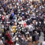 Visualization of coronavirus multiplying with a background of people at a train station concourse.