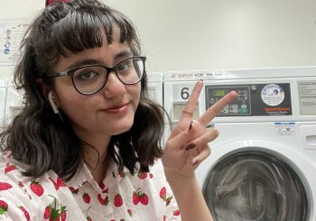 Leslie giving peace sign in front of washing machine