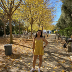 young woman standing on golden leaves with golden elm trees around