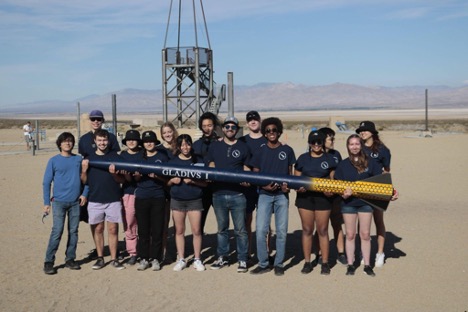group of students holding what looks like a giant pencil