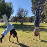 two students doing handstands outside