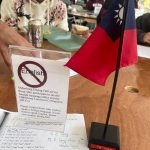 flag of Taiwan on a table with sign advising not to speak English